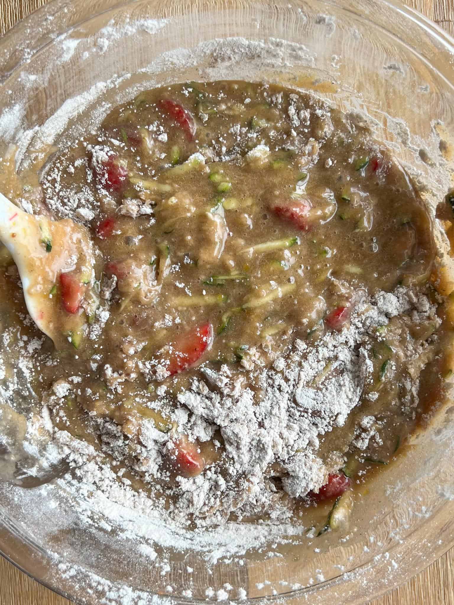 mixing in the flour to the batter in a glass bowl