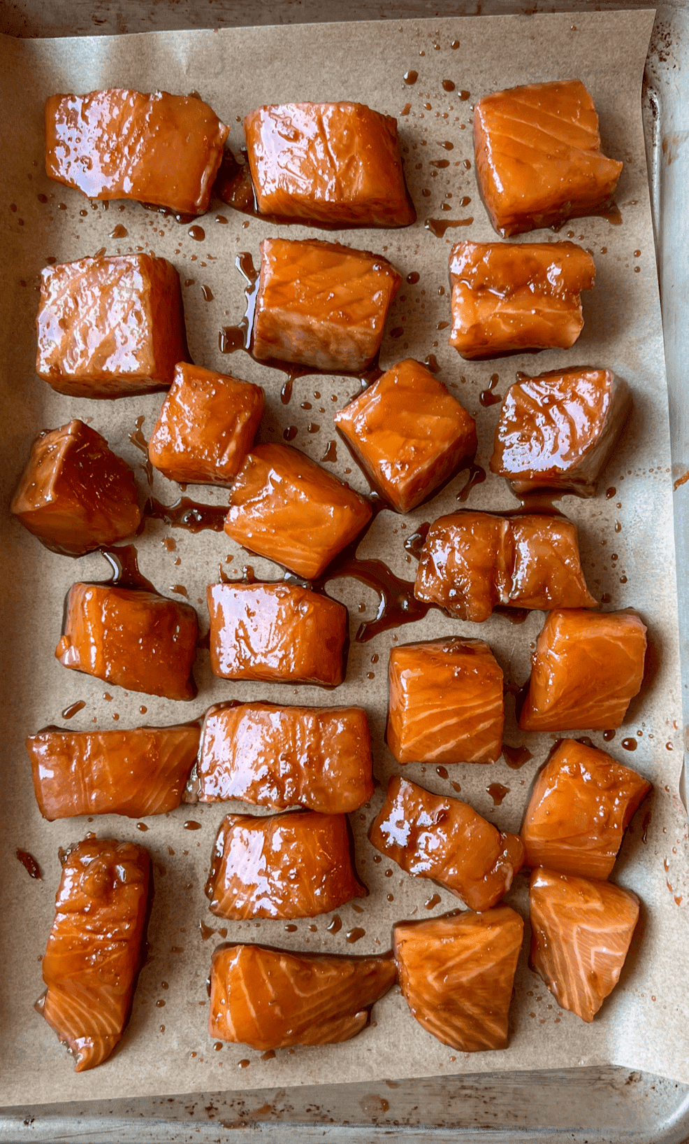 Orange Sesame Salmon Bites 7 Marinated salmon bites on a sheet tray