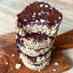 Maple Tahini Oat Cups 8 Maple tahini oatmeal cups stacked with one bite taken