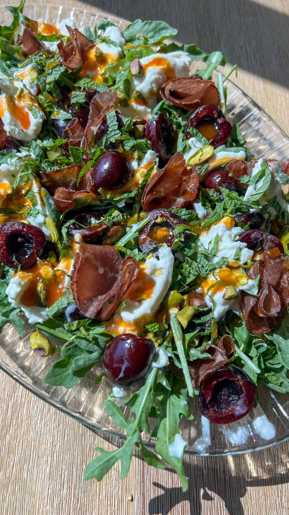 Summer Cherry and Burrata Salad 3 Close up of the summer cherry and burrata salad with bresaola, mint, pistachios, and hot honey dressing