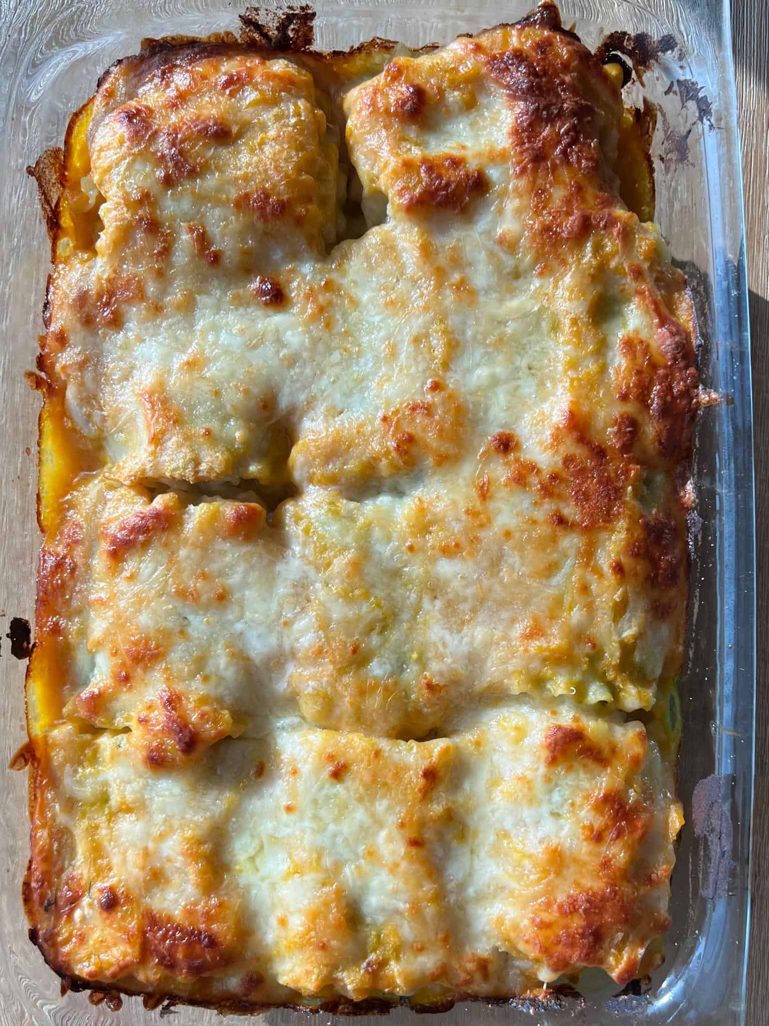 Butternut Squash and Spinach Lasagna Rollups 5 A glass baking dish with the cooked butternut squash and spinach lasagna roll ups cooked with melty cheese on tip.