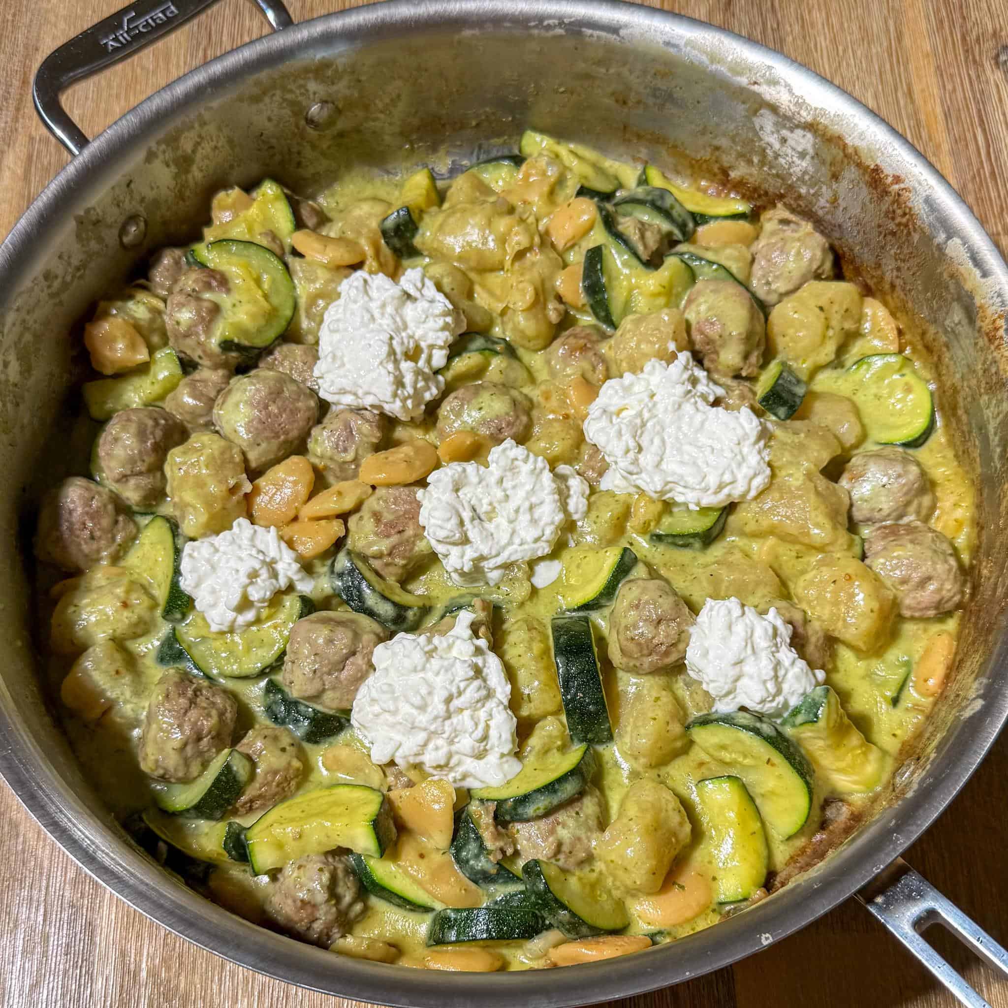 Healthy Pesto Gnocchi and Meatballs 9 Pan no longer on the heat. Stracciatella has been dolloped in 6 spots on the dish.