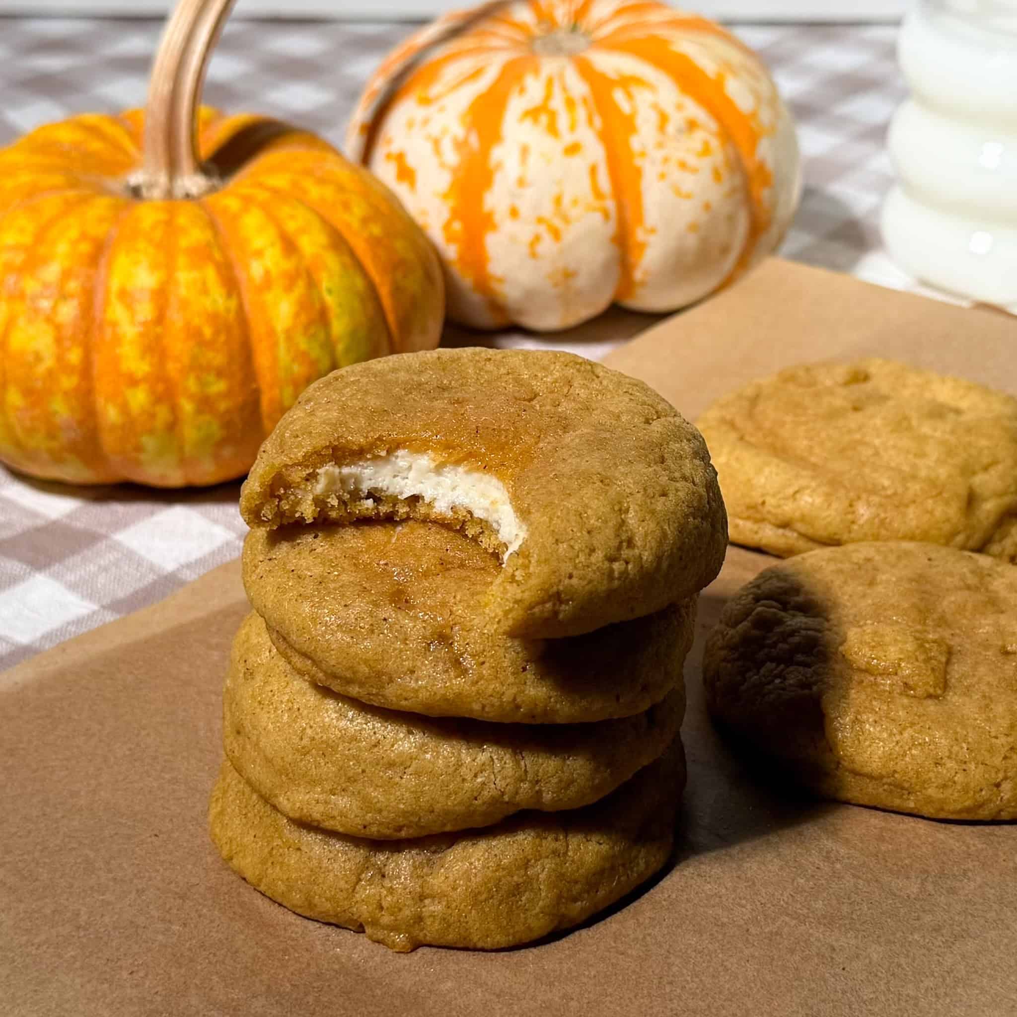 pumpkin chai cheesecake stuffed cookies stacked with a bite taken off the top cookie