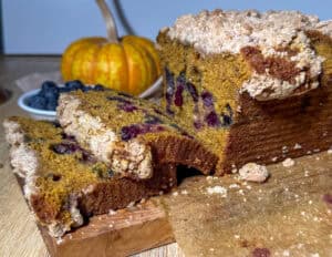 Slices of pumpkin blueberry bread with brown butter streusel served on a cutting board.