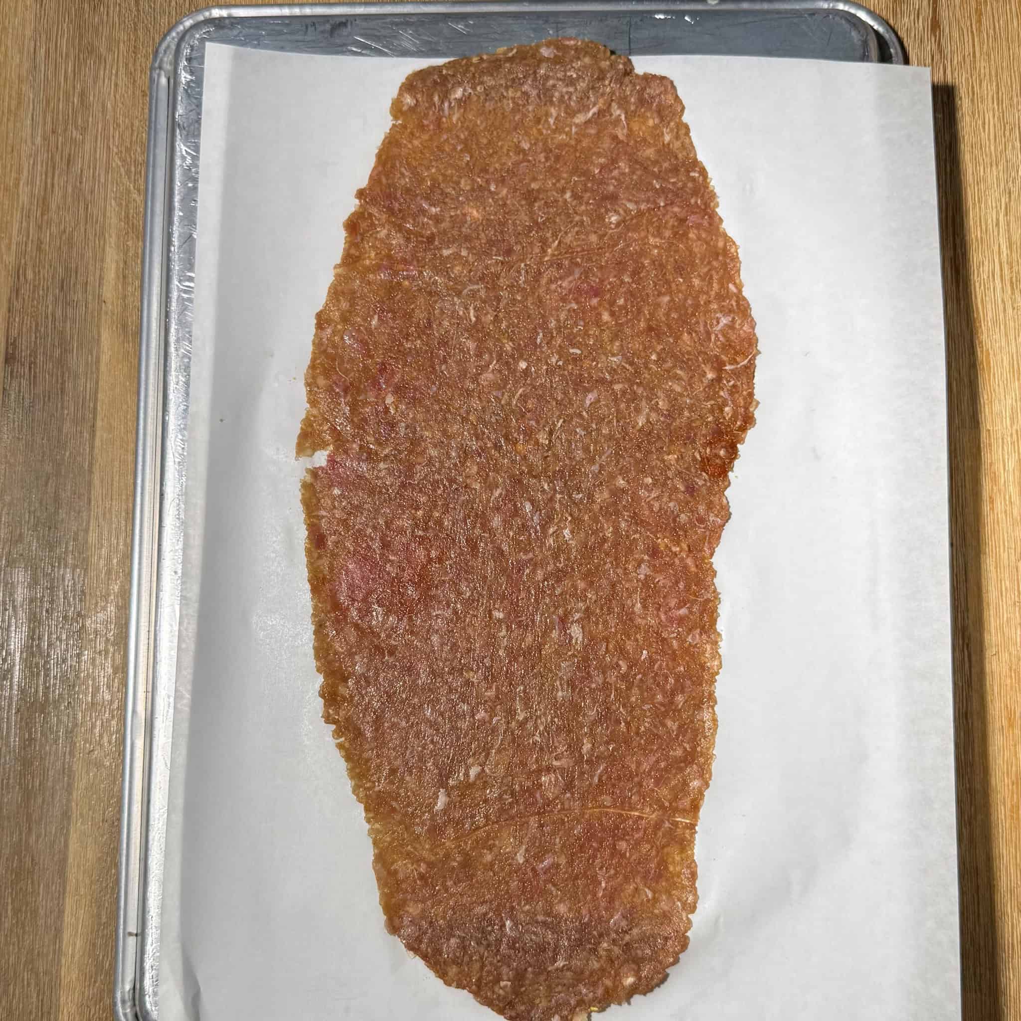 Rolled and flattened ground meat mixture on a parchment paper