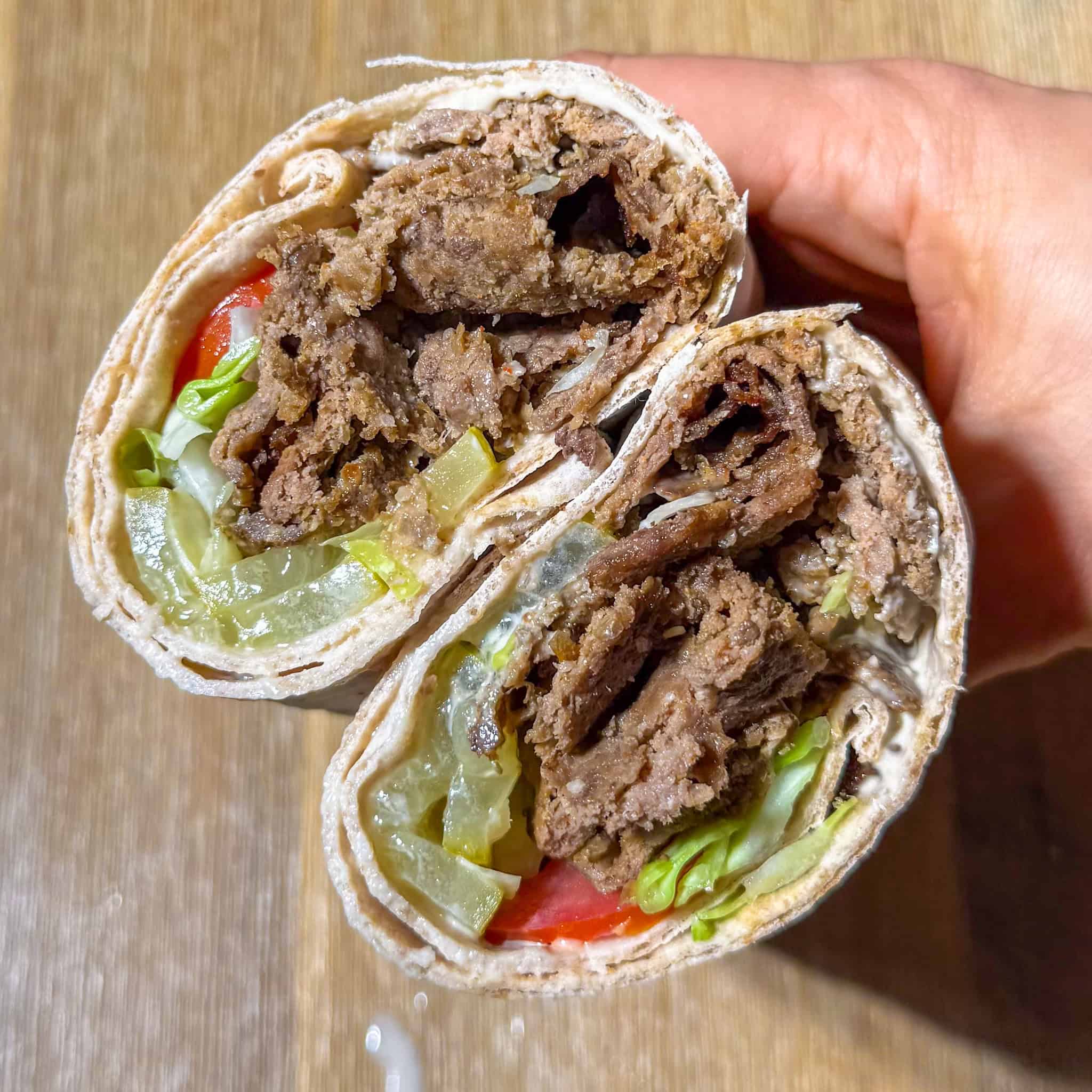 Viral oven baked doner kebabs in a lavash wrap with vegetables, pickles, and tahini,