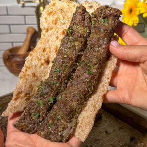 two pieces of baked sheet pan koobideh kabob in bread